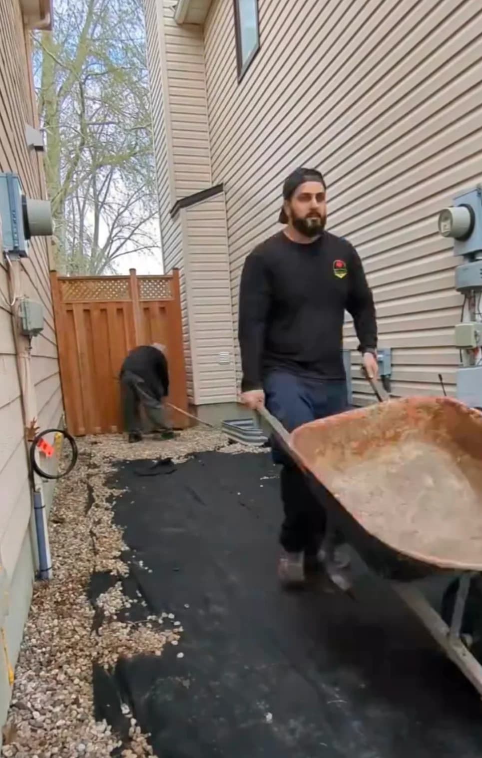 Adel transporting landscape materials with a wheelbarrow alongside a crew member on an Ottawa property