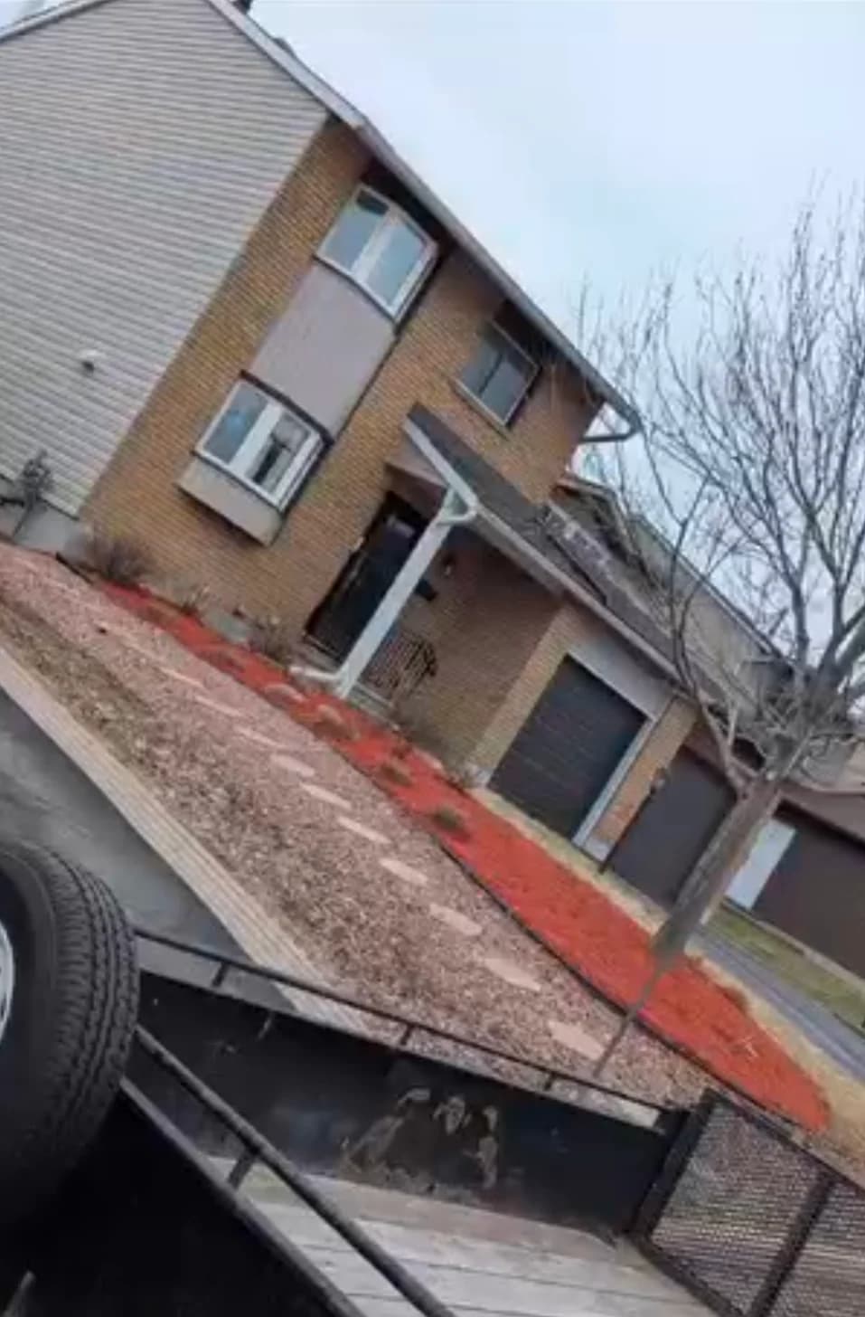 Red mulch garden bed and stepping stone pathway viewed from equipment trailer at an Ottawa residential home