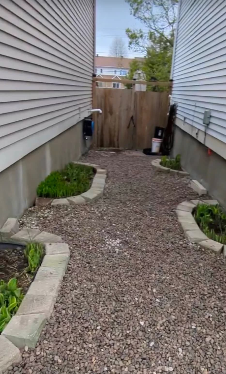 Narrow side yard transformed with decorative river rock pathway and retaining stone garden beds
