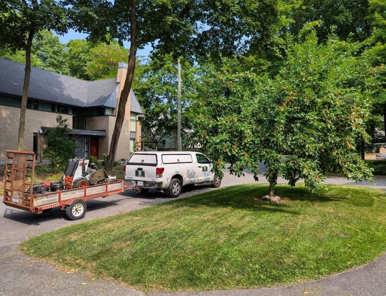 Company truck and equipment trailer parked beside a freshly mowed lawn at an Ottawa property